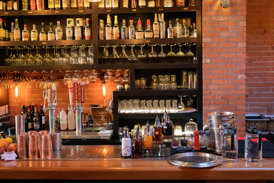 The back bar at El Moro Spirits & Tavern, lined with bottles and hanging stemware