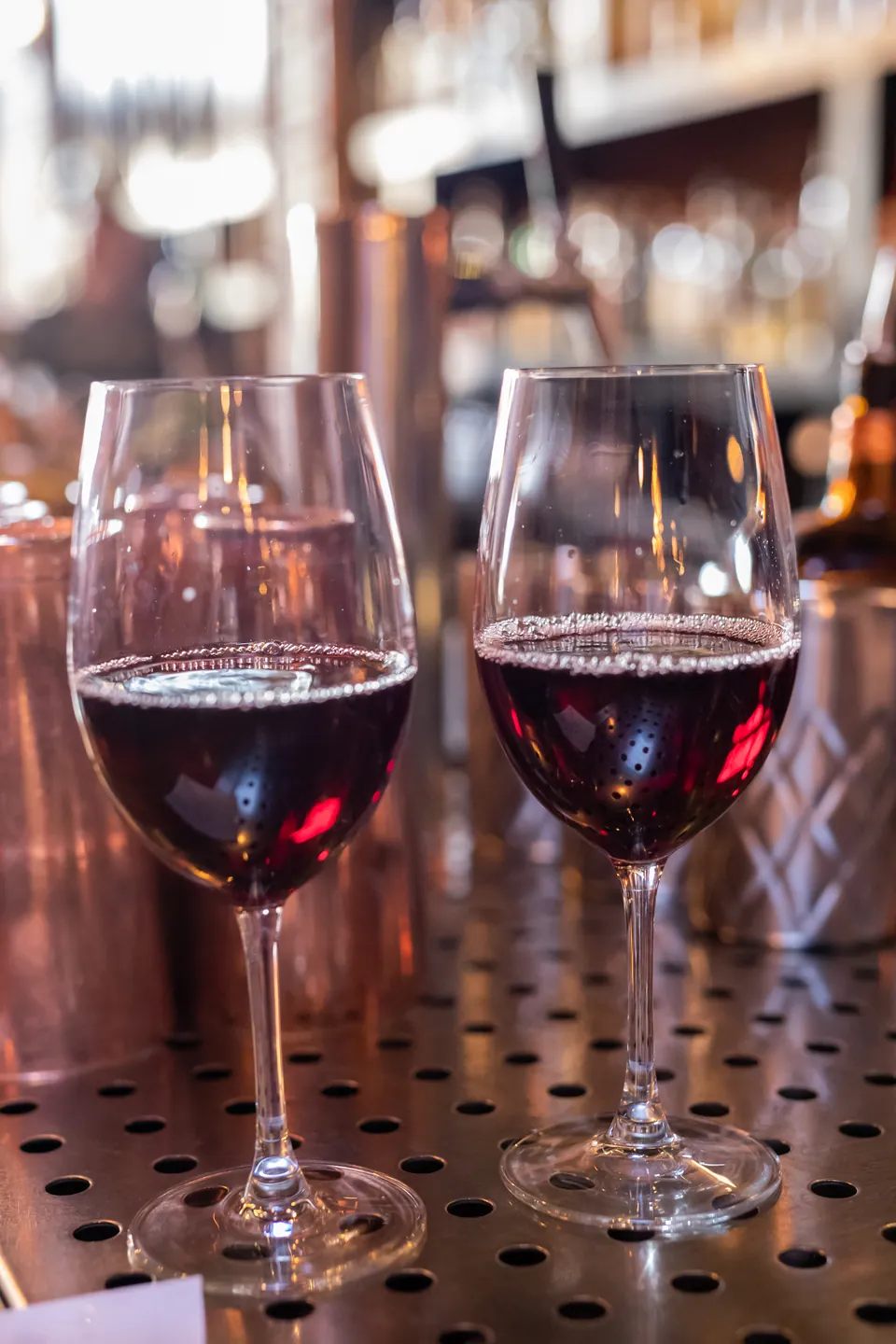 Two glasses of red wine on El Moro's copper-lit bar